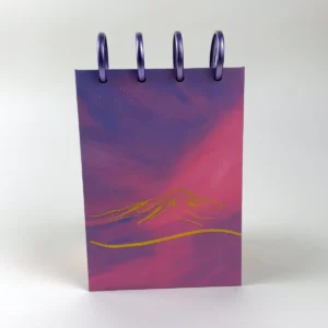 Libreta A6 Villarica Sunset con paisaje de montaña en tonos morados y rosados y discos superiores